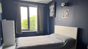 A bedroom with a bed, a window with curtains, a radiator, and wall decorations. - 🏈 American College Football Fans - 2027 Aer Lingus College Football Classic 🏈 (Dublin)