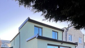 A modern two-story house with a patio area, large sliding glass doors, and outdoor furniture. - 🏈 American College Football Fans - 2027 Aer Lingus College Football Classic 🏈 (Dublin)
