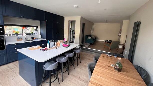 A modern kitchen with dark cabinets, a white island, and bar stools. - 🏈 American College Football Fans - 2027 Aer Lingus College Football Classic 🏈 (Dublin)