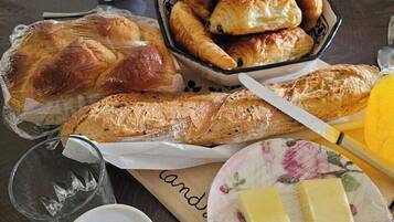 Une table avec divers produits de boulangerie, notamment des croissants et du pain, une assiette avec du beurre et un verre.