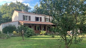 Una casa de dos pisos con techo de tejas, un porche delantero y un césped cuidado.