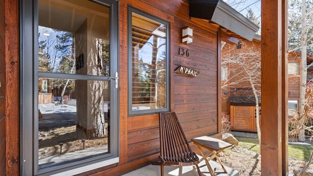 A wooden cabin with a large sliding glass door, a wooden chair, and a small table outside. - Elevated Tahoe Escape (Incline Village)