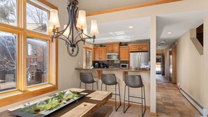 A modern kitchen with wooden cabinets, a central island with bar stools, and a chandelier. - Elevated Tahoe Escape (Incline Village)