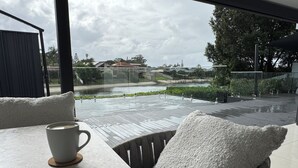 A modern outdoor seating area with a view of a lake and surrounding greenery. - Waterfront retreat with jetty, pool, waterslide and luxury comfort. (Mermaid Waters)