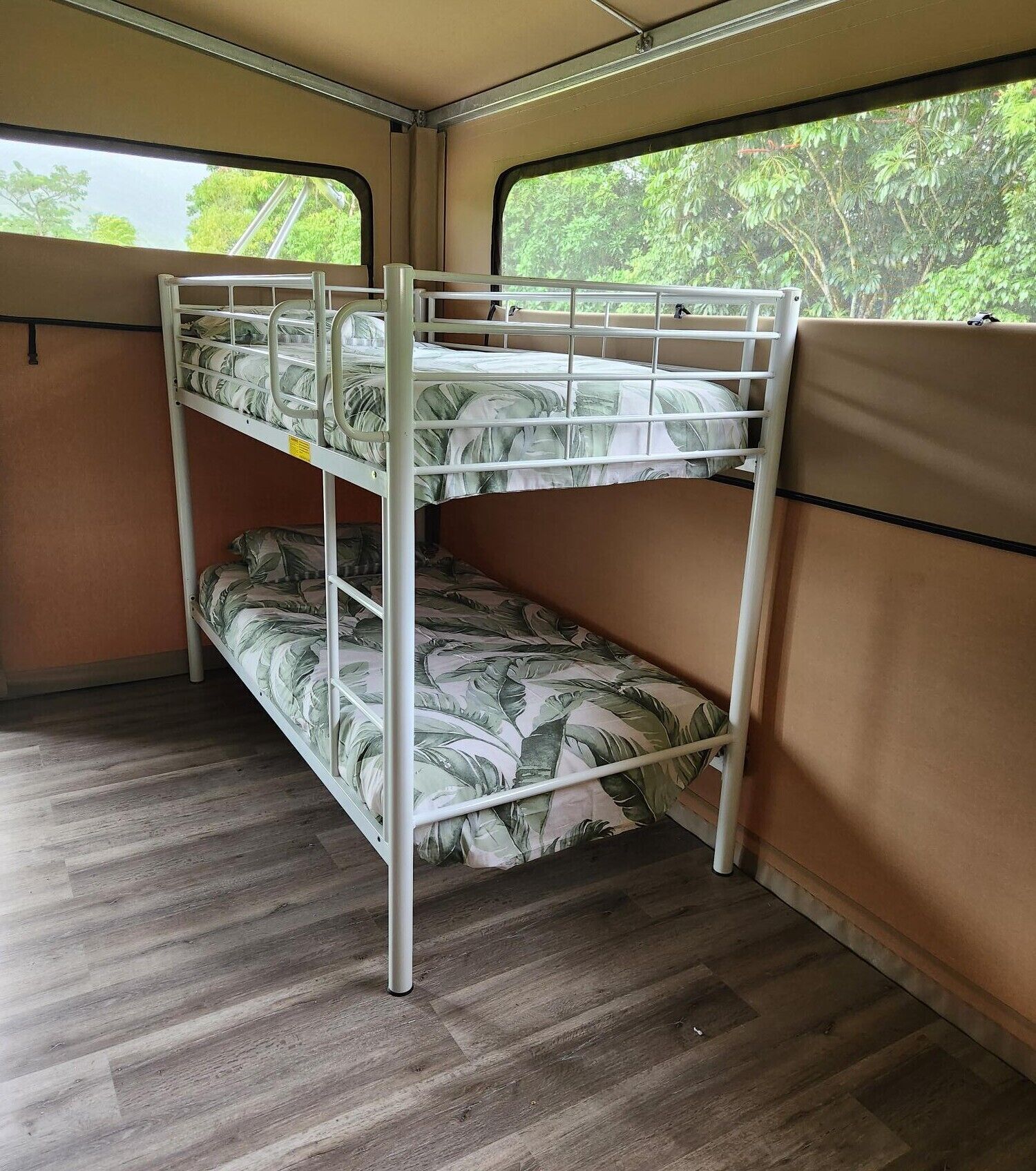 A bunk bed with a leaf-patterned mattress in a room with wooden flooring and beige walls.