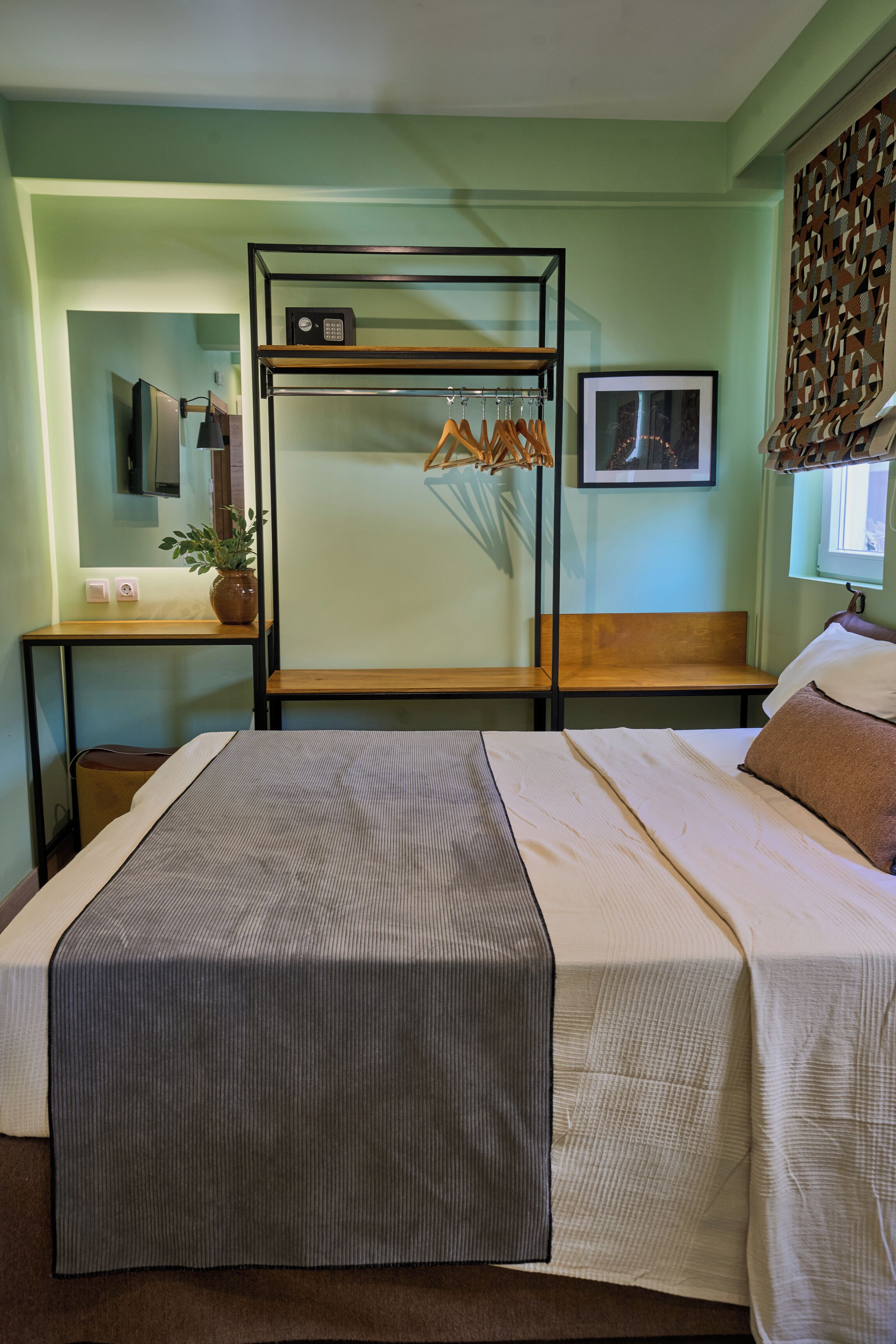 Una habitación con una cama litera, un escritorio con una computadora, una silla, una planta y un cuadro en la pared.