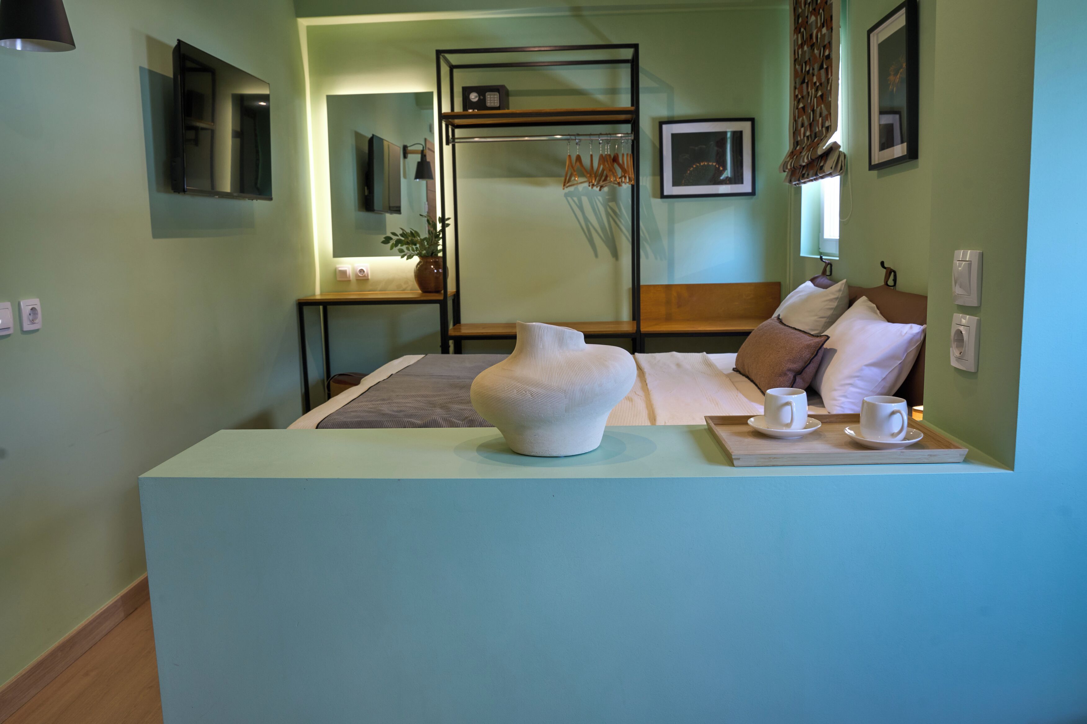 A hotel room with a bed, bedside table, lamp, and a decorative vase.