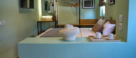 A hotel room with a bed, bedside table, lamp, and a decorative vase.