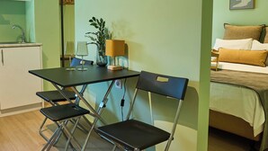 Un espace de vie compact comprenant un coin cuisine, un espace repas avec une table et des chaises, et un lit avec des oreillers.