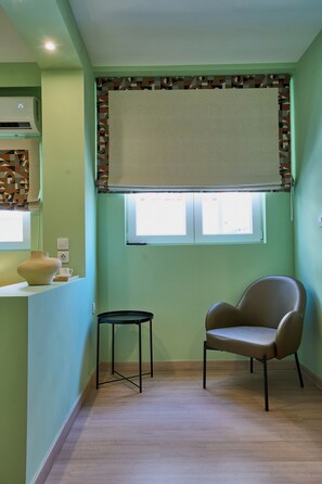 A room with a window, a chair, a small table, and a wall-mounted air conditioner. - Harmony 89 (Palaio Faliro)