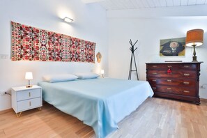 A bedroom with a bed, a nightstand, a dresser, a wall tapestry, and a coat rack. - Elegant attic apartment, recently renovated with high-quality finishes, comfortably accommodates 4 people in 150 square meters, with two double bedrooms and two bathrooms. Located in a quiet hillside neighborhood of Salerno, it features a small terrace w (Salerno)