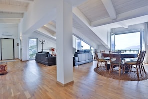 A spacious loft-style living area with high ceilings, a dining table with chairs, and a large window offering a view. - Elegant attic apartment, recently renovated with high-quality finishes, comfortably accommodates 4 people in 150 square meters, with two double bedrooms and two bathrooms. Located in a quiet hillside neighborhood of Salerno, it features a small terrace w (Salerno)