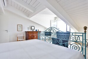 Ein Schlafzimmer mit Bett, Kommode, Stuhl und Fenster mit Blick.