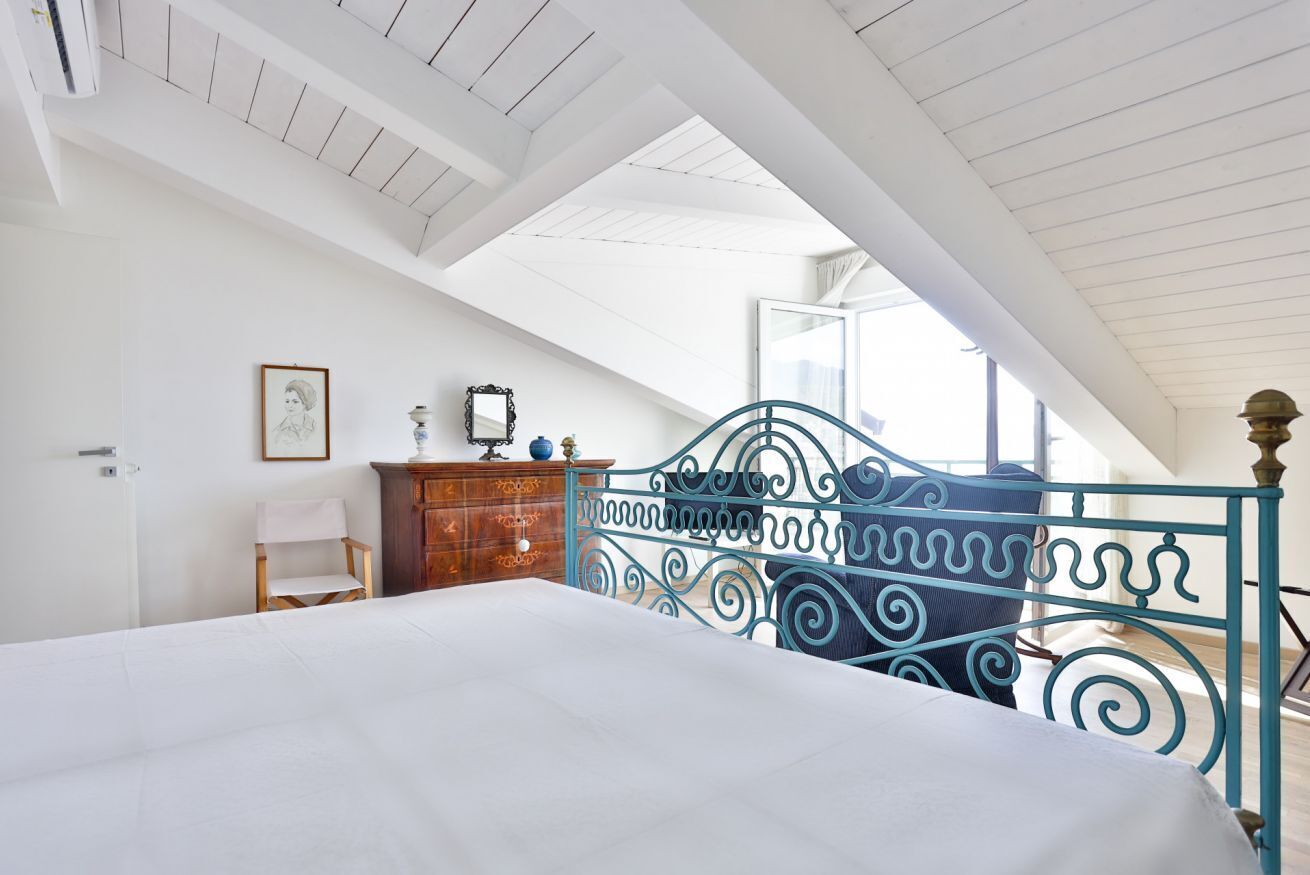 Un dormitorio con cama, cómoda, silla y ventana con vistas.