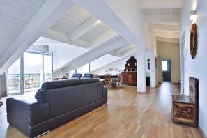 Ein geräumiges Loft mit einem großen schwarzen Sofa, Holzboden und einem Essbereich mit Stühlen und einem Tisch.