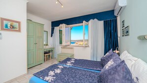 Ein Schlafzimmer mit Bett, Schreibtisch, Stuhl, Fenster mit Aussicht und Klimaanlage.