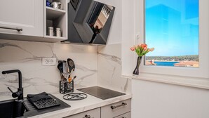 Ett modernt kök med en bänkskiva i marmor, en inbyggd spis och ett fönster med utsikt över havet.