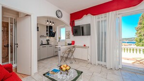 Eine moderne Küche mit Essbereich, einem Fernseher und Blick auf das Meer.