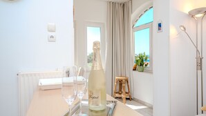 Una habitación con una mesa dispuesta para una comida, una botella de Freixenet champagne y vistas al mar a través de una ventana.