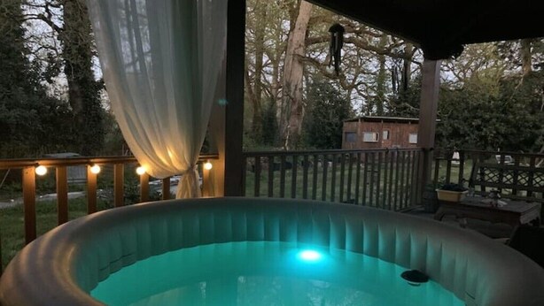 A hot tub with a view of trees and a wooden deck.