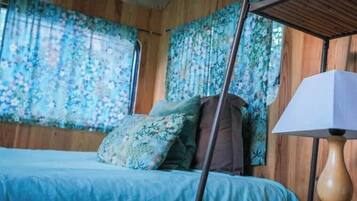 Een slaapkamer met een bed, een nachtkastje, een lamp en bloemen gordijnen.