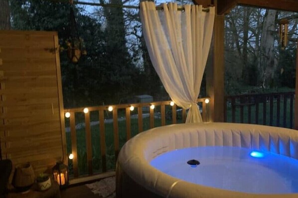 A hot tub in a covered outdoor area with a wooden deck and string lights.