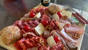 A charcuterie board with various meats, cheeses, and bread on a wooden table.