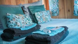 A neatly made bed with floral-patterned pillows and a blue bedspread.