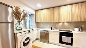 Een moderne keuken met roestvrijstalen apparatuur, houten kastjes, een wasmachine en een vaatwasser.