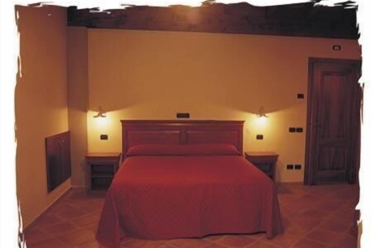 A bedroom with a large bed, two bedside tables, and two wall-mounted lights.