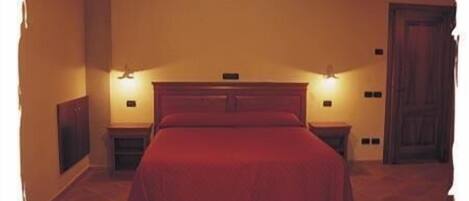 Un dormitorio con una cama grande, dos mesitas de noche y dos luces fijadas a la pared.