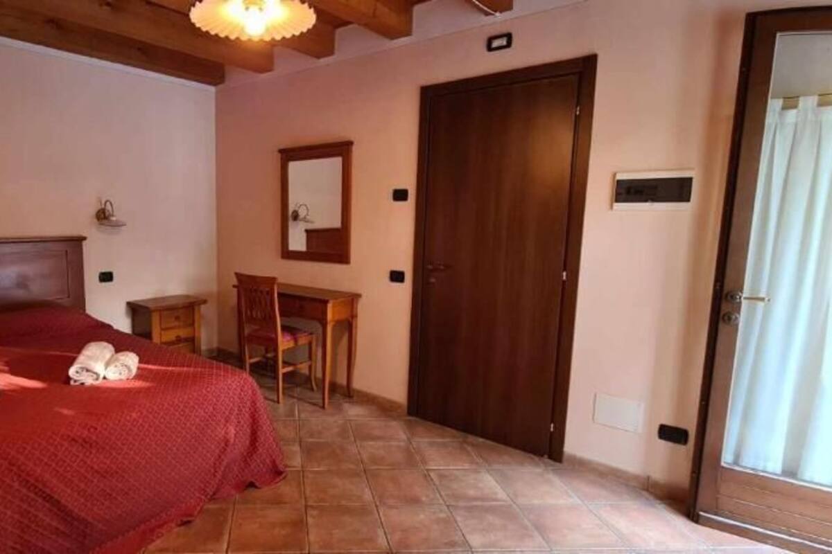 A bedroom with a wooden bed, a desk, a chair, and a door.