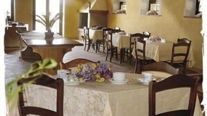 A dining area with tables set for a meal, chairs, and a vase of flowers. - Corte Belvedere (Sommacampagna)