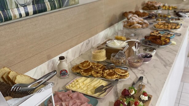 A buffet with various food items, including sandwiches, meats, and pastries.