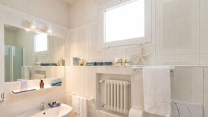 A bathroom with a sink, mirror, towel rack, and a window.