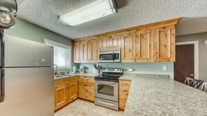 Eine Küche mit Holzschränken, einem Edelstahlkühlschrank, einer Mikrowelle, einem Backofen und Granit-Arbeitsplatten.