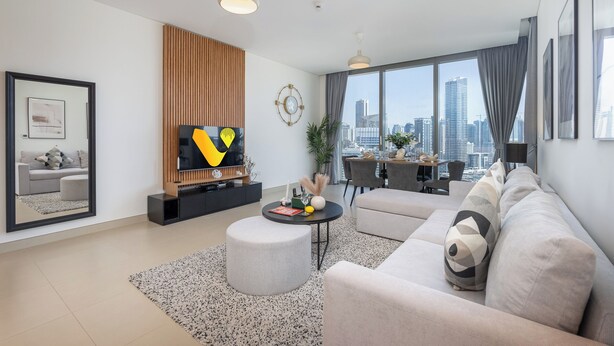 A modern living room with a sofa, ottoman, and a TV on a wooden stand. - Vogue | 52 | 42 Marina near Ain Dubai | JBR Beach (Dubai)