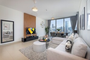 A modern living room with a sofa, ottoman, and a TV on a wooden stand. - Vogue | 52 | 42 Marina near Ain Dubai | JBR Beach (Dubai)