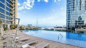 A swimming pool area with lounge chairs and a view of the city skyline. - Vogue | 52 | 42 Marina near Ain Dubai | JBR Beach (Dubai)