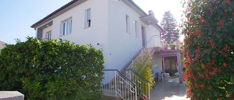 A two-story house with a white exterior, a balcony, and a small patio area.
