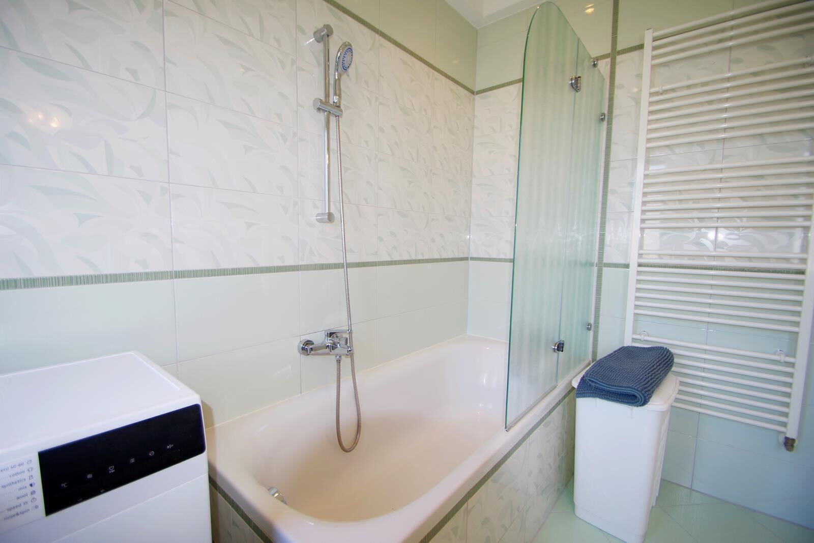A modern bathroom with a glass-enclosed shower, a standalone bathtub, and a built-in washing machine.
