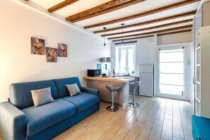 Eine moderne Küche mit Holzbalken, einem blauen Sofa und einer kleinen Bar.