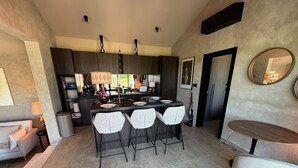 A modern kitchen with a central island, bar stools, and a dining table with chairs. - 2-bedroom Poolvilla in Rovinj with cool AC breeze (Rovinj)