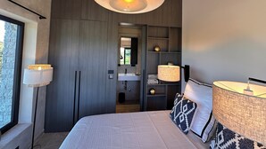 A modern bedroom with a large bed, bedside lamps, a built-in wardrobe, a vanity with a mirror, and a view through an open door. - 2-bedroom Poolvilla in Rovinj with cool AC breeze (Rovinj)