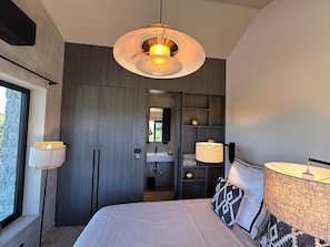 A modern bedroom with a large bed, bedside lamps, a built-in wardrobe, and a view through a window. - 2-bedroom Poolvilla in Rovinj with cool AC breeze (Rovinj)