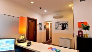 Ein Hotel-Empfangsbereich mit einem Schreibtisch, einem Computer, einer Lampe und einer Wandklimaanlage.