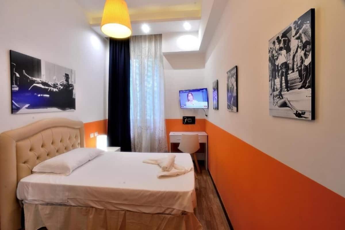 Una habitación de hotel con una cama, un escritorio y una televisión.