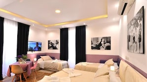 Ein Hotelzimmer mit zwei Betten, einem Schreibtisch mit Stuhl, einem Fernseher und Bildern an der Wand.