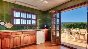 A kitchen with wooden cabinets, a dishwasher, and a window. - Beautiful House with Stunning Views (Calonge)