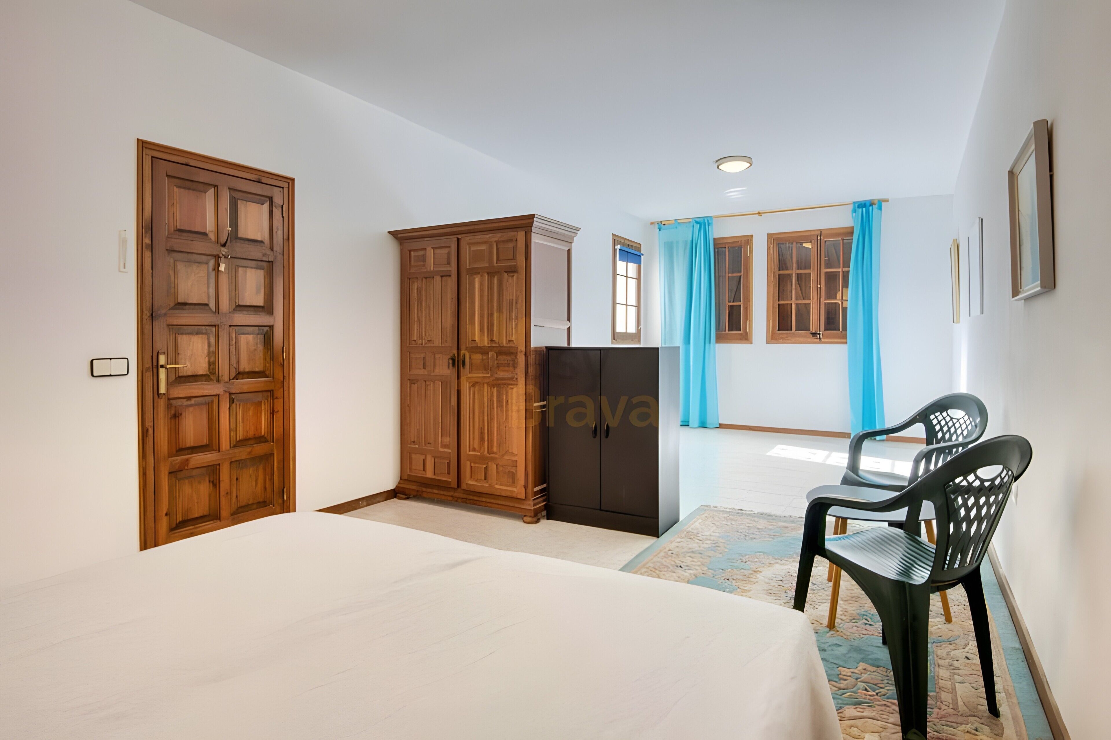 Un dormitorio con cama, armario y una silla.